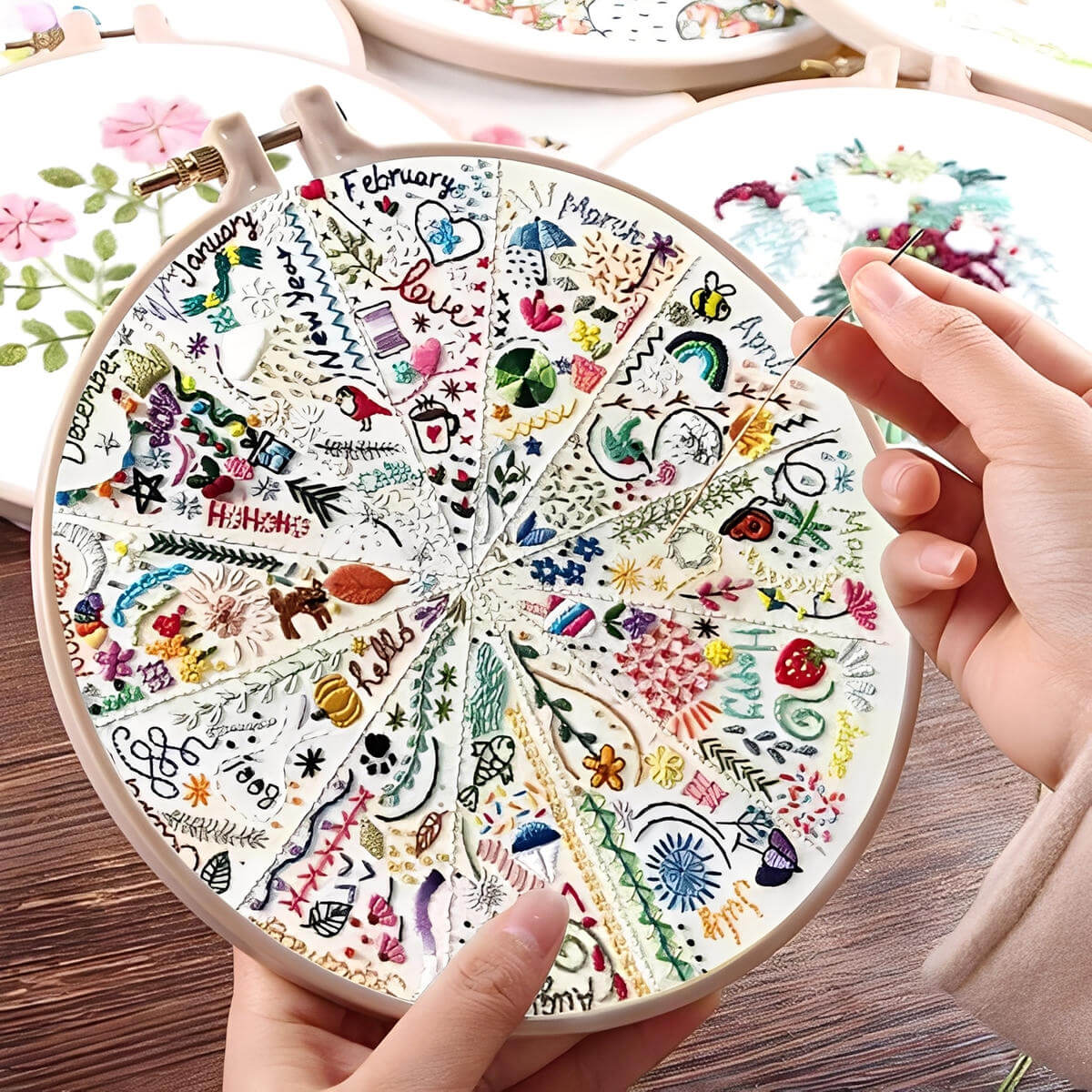 CraftHoop Advent of 12 Seasons Embroidery Kit featuring hands stitching seasonal designs in a circular hoop.
