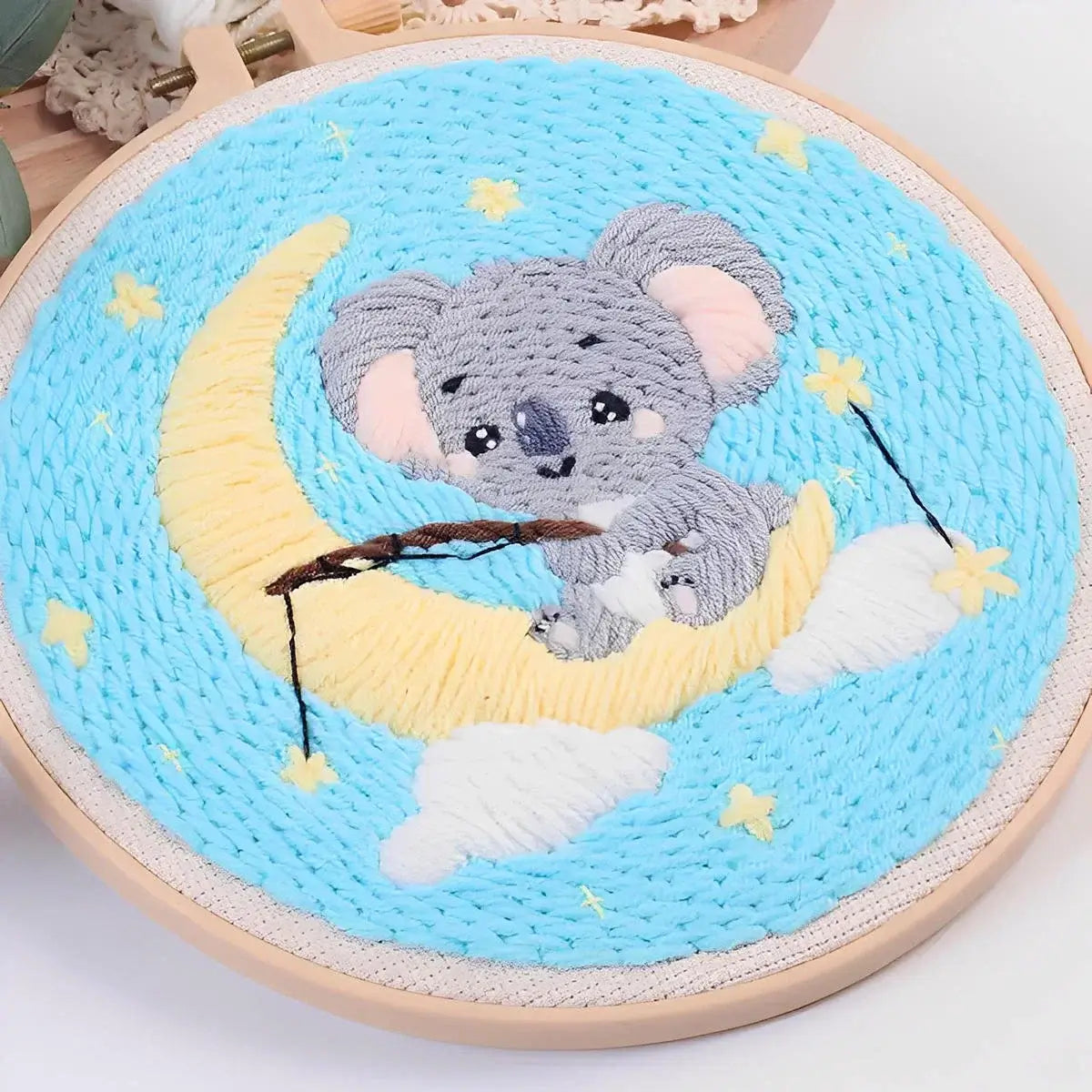 CraftHoop Cozy Koalas Punch Needle Kit featuring a koala sitting on a crescent moon with stars and clouds.