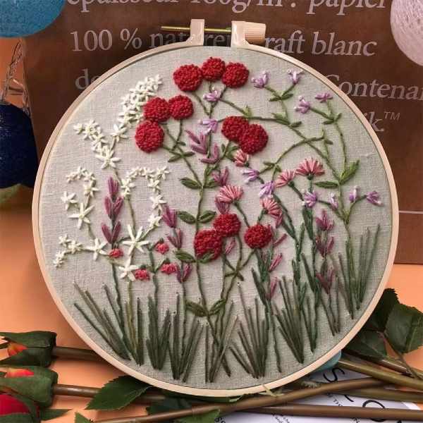 CraftHoop embroidery kit with a floral design featuring pink and white flowers with green leaves, displayed on a wooden hoop.