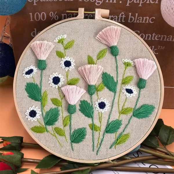 CraftHoop embroidery kit showcasing a detailed design of purple, white, and yellow flowers in a meadow setting, displayed on a wooden hoop.