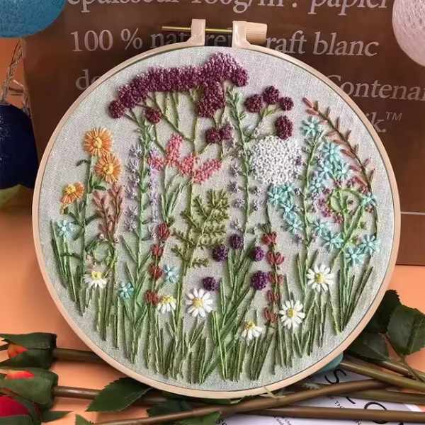 CraftHoop embroidery kit showcasing a meadow of wildflowers in pink, white, and purple tones, displayed on a wooden hoop.