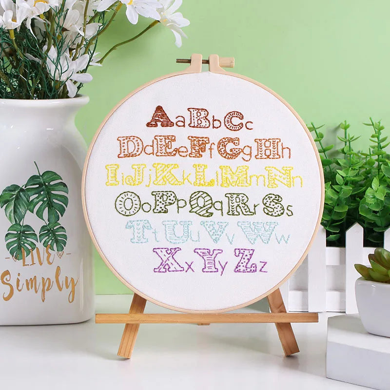 Display of completed CraftHoop Beginner's Alphabet Embroidery Kit with floral designs around the letters.