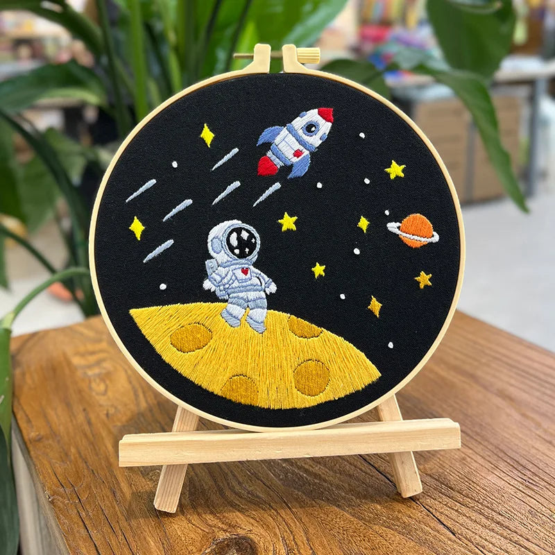 CraftHoop Little Astronaut Embroidery Kit displayed with space-themed embroidery on a wooden stand.