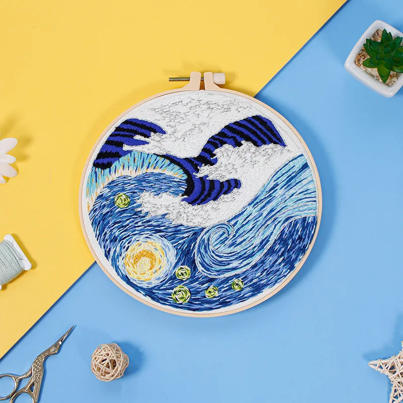 Close-up of CraftHoop starry night embroidery kit featuring a crescent moon and swirling clouds on blue fabric, displayed on a yellow and blue background