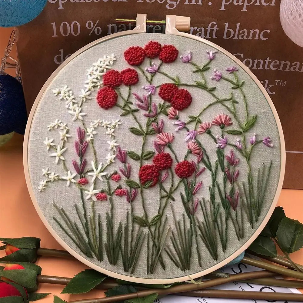 CraftHoop embroidery kit featuring a wildflower meadow design with various flowers in green, white, purple, and yellow tones, displayed on a wooden hoop.