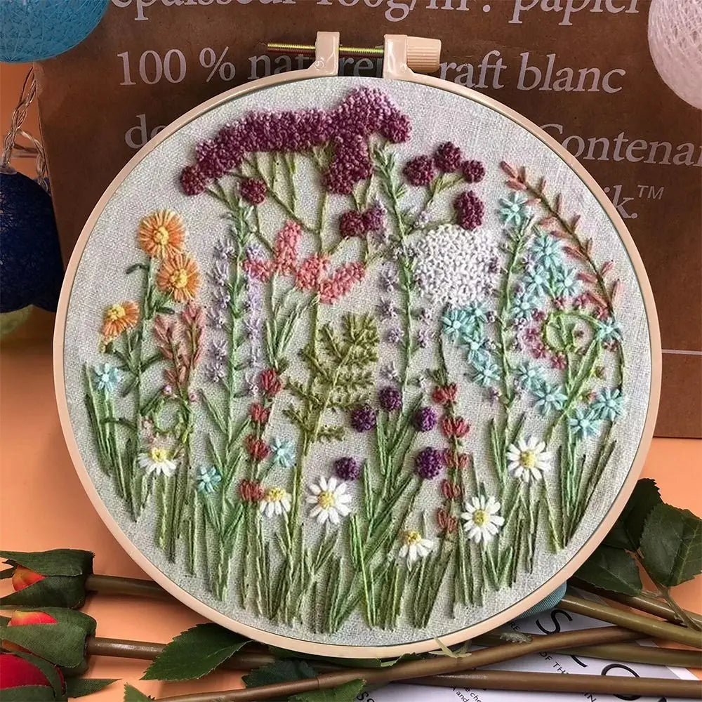 CraftHoop embroidery kit featuring a meadow of wildflowers in pink, white, and purple tones, displayed on a wooden hoop.