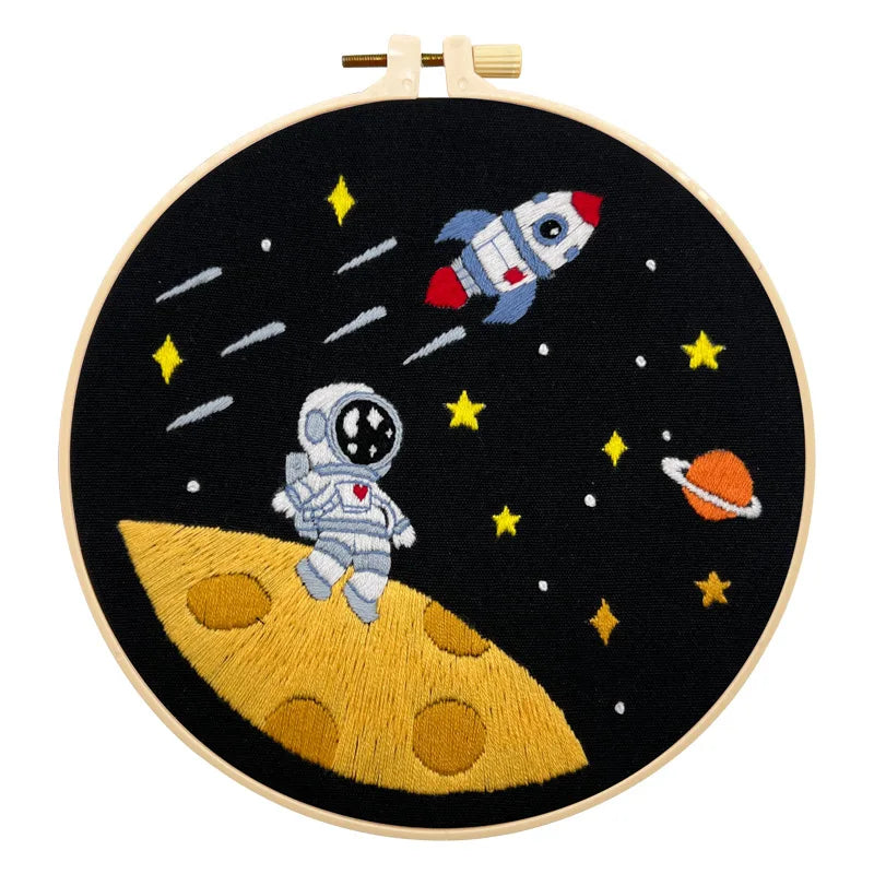 CraftHoop Little Astronaut Embroidery Kit with embroidered space elements, displayed on a wooden stand.