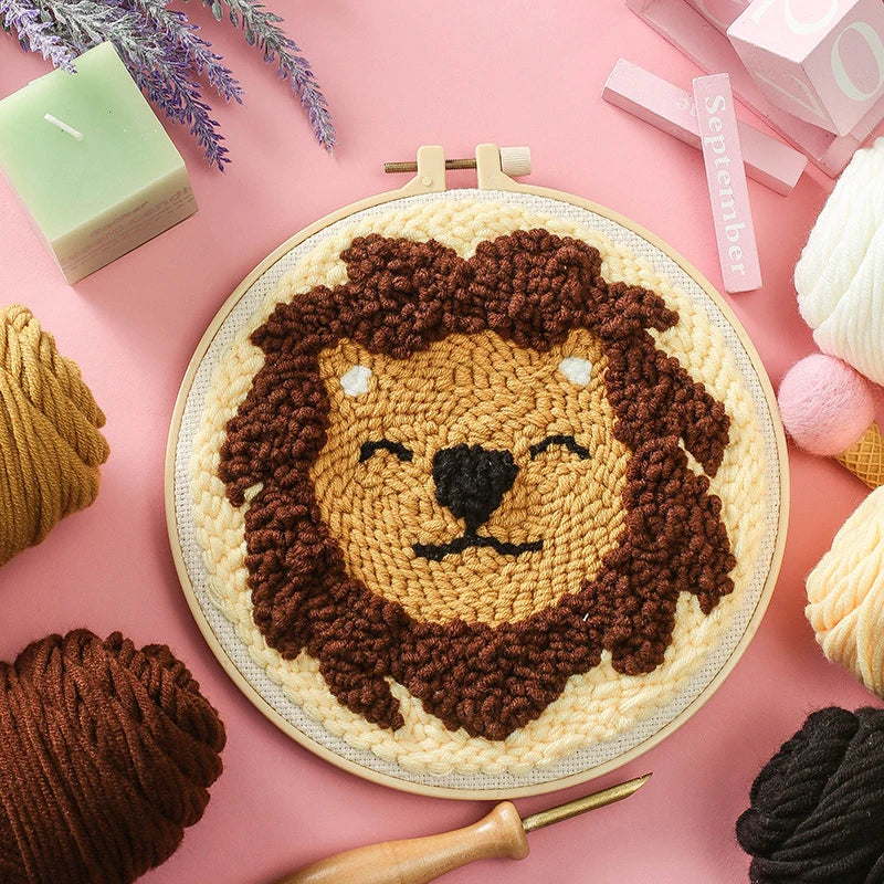 CraftHoop punch needle embroidery kit featuring an adorable sloth face design, displayed on a pink background with yarn and embroidery tools.