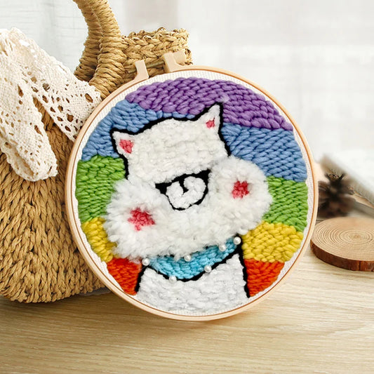 CraftHoop punch needle embroidery kit featuring a colorful llama design with a rainbow background, displayed on a wooden surface.