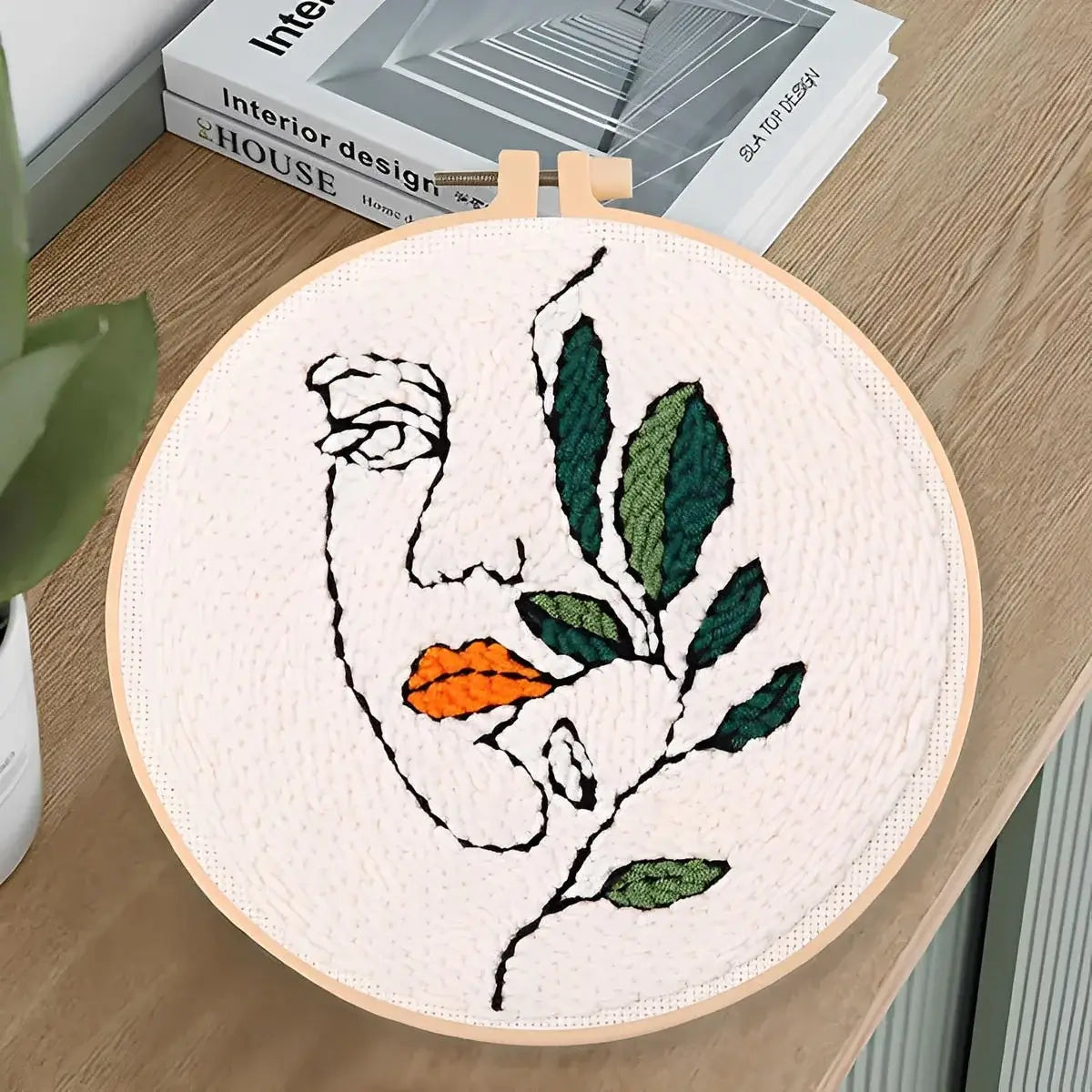 CraftHoop Botanical Muse Punch Needle Kit showcasing abstract face with greenery on a wooden table.