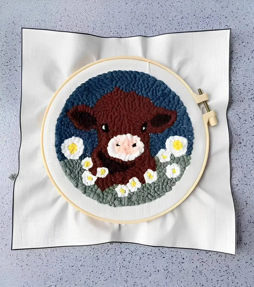 CraftHoop Farm Friends Punch Needle Kit featuring a cute brown cow surrounded by white flowers in a colorful textile design.