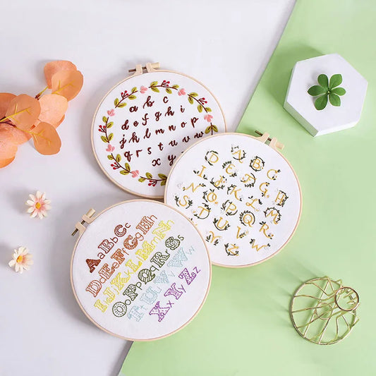 CraftHoop Beginner's Alphabet Embroidery Kit with colorful alphabet designs displayed on a wooden stand.